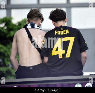 Manchester, Regno Unito. 12th giugno, 2023. I fan di Man City si siedono su un cartellone pubblicitario per vedere la parata di vittoria dell'autobus scoperto nel centro di Manchester, nel Regno Unito, per segnare il successo del loro club vincendo gli alti: La Premier League, la fa Cup e la Champions League. Il sabato Man City ha battuto l'Inter Milan a Istanbul per assicurarsi la vittoria della Champions League. La sfilata di autobus scoperti passava per il centro di Manchester, sotto la vista di grandi folle entusiaste, nonostante la tempesta e la pioggia intensa. Credit: Terry Waller/Alamy Live News Foto Stock