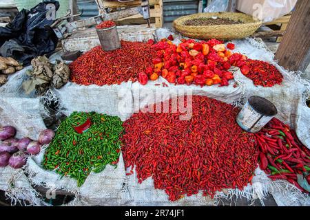 Toliara, Madagascar - 01 maggio 2019: Peperoni secchi rossi e verdi e spezie, in colori vivaci di contrasto, esposti sul terreno del mercato alimentare di strada Foto Stock