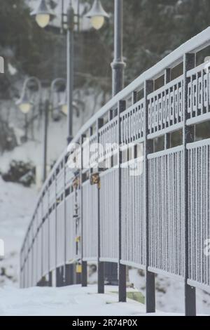 Un sentiero innevato si estende lungo una ringhiera metallica, in un ambiente meraviglioso d'inverno Foto Stock