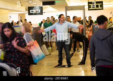 Le persone che passano attraverso controlli di sicurezza all'interno dell'aeroporto di Cancun, in Messico, vengono controllate con un rilevatore di metalli Foto Stock