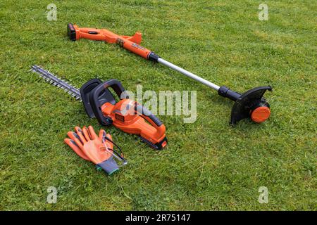 Il tagliasiepi e il tagliaerba cordless Black & Decker si trovano sul prato, sulla cura del prato, sul giardino, Foto Stock