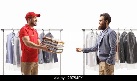 Uomo che dà un mucchio di vestiti di pulitura a secco ad un cliente maschio isolato su uno sfondo bianco Foto Stock