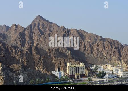 Una vista panoramica di un paesaggio urbano con montagne frastagliate sullo sfondo a Muscat, Oman Foto Stock