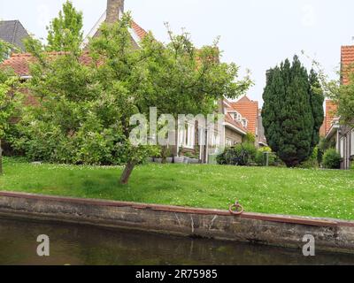 Un tranquillo paesaggio rurale caratterizzato da un pittoresco villaggio accoccolato vicino a un corpo tranquillo di acqua Foto Stock
