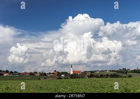 Cumulonimbus nuvole sopra un villaggio, Germania, Baviera, Voralplenland, Kirchdorf/Haag Foto Stock