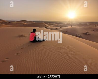 Una carovana di dromedari che passa il deserto del Sahara in serata, Erg Chebbi in Marocco Foto Stock