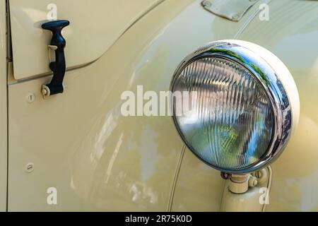 Faro luminoso rotondo sull'ala di un'auto d'epoca gialla. Primo piano. Foto Stock