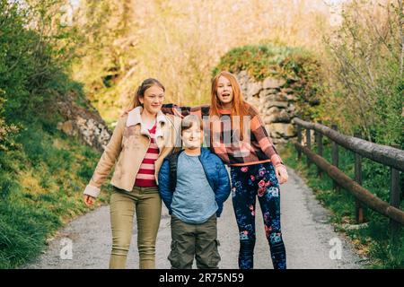 Gruppo di 3 bambini divertenti che giocano insieme in campagna, moda primaverile per bambini Foto Stock