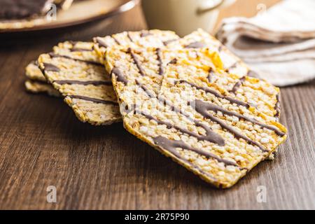 Cracker di mais soffiato cioccolato coperto sul tavolo di legno. Foto Stock