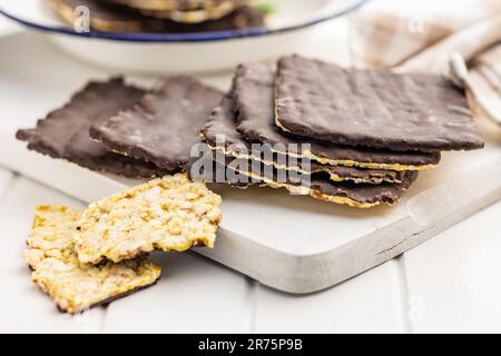 Cracker di mais soffiato cioccolato coperto sul tavolo bianco. Foto Stock