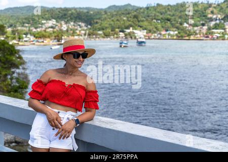 Nord America, Caraibi, grandi Antille, Isola di Hispaniola, Repubblica Dominicana, Provincia di Sama, Penisola di Sama, Santa rbara de Sama, Pretty Latina appoggiata sulla ringhiera del ponte nella Baia di Sama Foto Stock