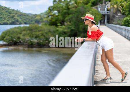 Nord America, Caraibi, grandi Antille, Isola di Hispaniola, Repubblica Dominicana, Provincia di Sama, Penisola di Sama, Santa rbara de Sama, Pretty Latina appoggiandosi sulla ringhiera del ponte iconico e guardando la Baia di Sama Foto Stock