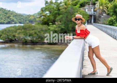 Nord America, Caraibi, grandi Antille, Isola di Hispaniola, Repubblica Dominicana, Provincia di Sama, Penisola di Sama, Santa rbara de Sama, Baia di Sama, Pretty Latina appoggiata sulla ringhiera del ponte iconico Foto Stock