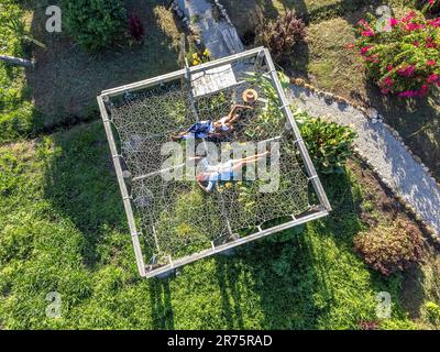 Nord America, Caraibi, grandi Antille, Isola di Hispaniola, Repubblica Dominicana, Provincia di Sama, penisola di Sama, El Limón, donne Pretty sdraiate su un'enorme amaca in Sama Eco Lodge Foto Stock