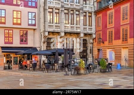 Oviedo, Asturias, Spagna - 12 febbraio 2023: Facciata di un edificio colorato con area salotto all'aperto. Un uomo si siede sotto un telo ombrello, godendosi il t Foto Stock