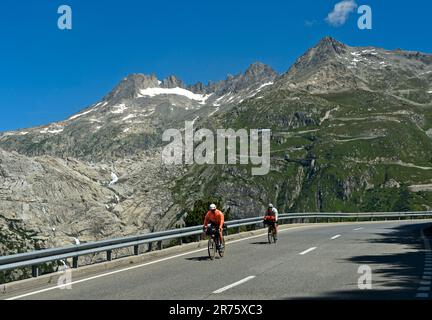 Ciclista sulla discesa dal Passo Furka, sul retro il letto ghiacciato del ghiacciaio del Rodano, strada Furkapas vicino a Gletsch, Vallese, Svizzera Foto Stock