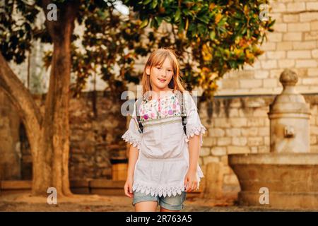 Adorabile ragazza turista con zaino per le strade della Provenza al tramonto, viaggio con i bambini Foto Stock