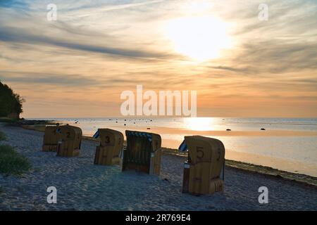 Sedia da spiaggia nella sabbia di fronte al Mar Baltico sull'isola di Poel al tramonto. Vista sul mare. Paesaggio girato dalla costa Foto Stock
