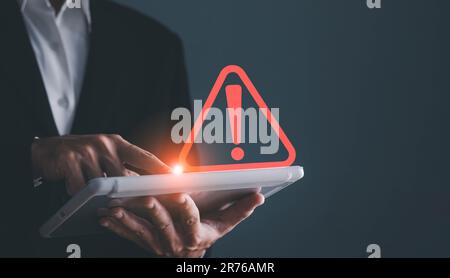 Uomo d'affari che utilizza un tablet con un triangolo di avviso di avviso per errore di notifica e concetto di manutenzione. Foto Stock