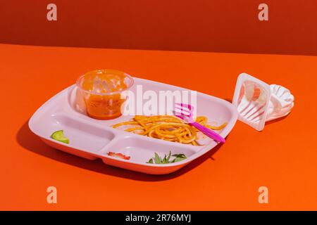 Da sopra gli avanzi di appetitosi spaghetti con fettine di cetriolo e fragola in salsa di pomodoro a forchetta servite per pranzo con vasetto di gelatina vuoto Foto Stock
