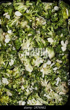 Dall'alto i broccoli verdi con formaggio e pepe posti su fondo ligneo in preparazione alla cottura Foto Stock