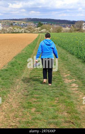 Donna cammina senza scarpe su una strada sterrata Foto Stock