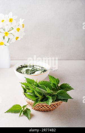 Giovani foglie di Nettle Shoot per un piatto sano su sfondo luminoso tavolo. Primavera sano disintossicazione alimentare Foto Stock