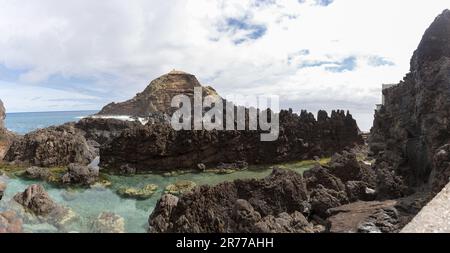 Isola di Madeira Portogallo - 04 19 2023: Vista delle piscine naturali sul villaggio di Porto Moniz, formata da rocce vulcaniche, isoletta di Mole sullo sfondo, Foto Stock