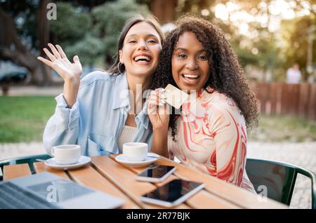 Pagamenti facili. Due donne che mostrano una carta di credito mentre si siedono al Cafe Outdoor Foto Stock