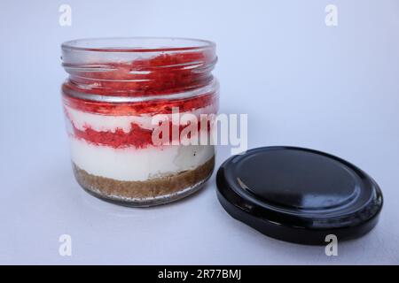 Deliziosa torta rossa in vaso di velluto con coperchio aperto isolato su sfondo bianco Foto Stock