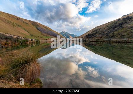 Fotografia del lago Kirkpatrick con le montagne che si riflettono nell'acqua in una giornata nuvolosa al di fuori di Queenstown, sull'isola meridionale della Nuova Zelanda Foto Stock