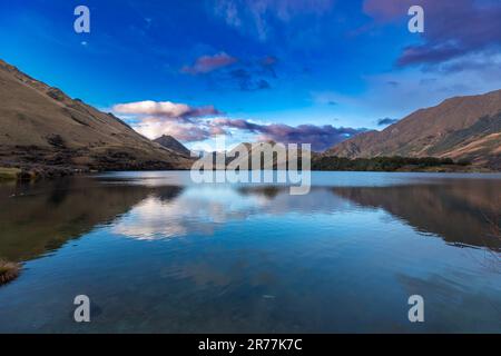 Fotografia del Lago Mike con le montagne che si riflettono nell'acqua in una giornata nuvolosa al di fuori di Queenstown, sull'Isola Sud della Nuova Zelanda Foto Stock