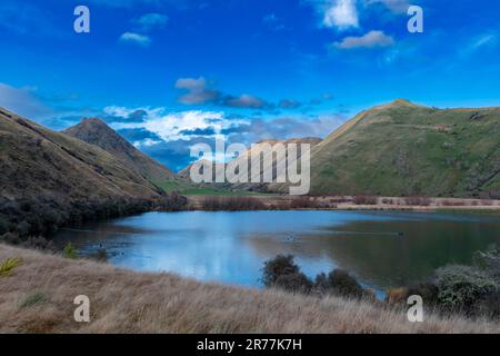 Fotografia del Lago Mike con le montagne che si riflettono nell'acqua in una giornata nuvolosa al di fuori di Queenstown, sull'Isola Sud della Nuova Zelanda Foto Stock