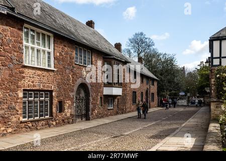 I pedoni passano davanti alle tradizionali vecchie case sulla chiusa ciottolata della Cattedrale di Exeter, Devon. Foto Stock