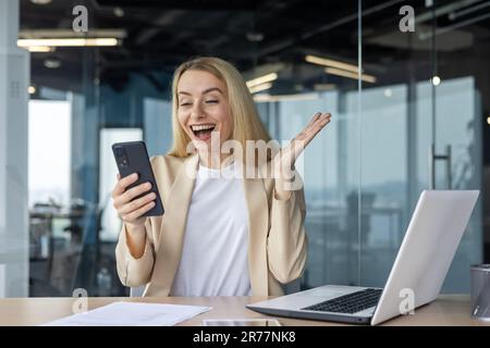 Boss felice di successo della donna sul posto di lavoro che celebra la vittoria ed i risultati riusciti di successo il lavoratore femminile in vestito ha ricevuto il messaggio in linea con il goo Foto Stock