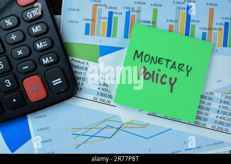 Concetto di politica monetaria scrivere su note appiccicose isolate su tavola di legno. Foto Stock