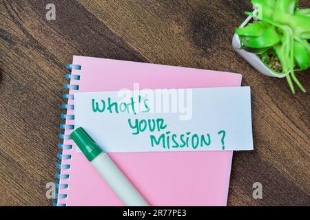 Concetto di Qual è la tua missione? Scrivete su note adesive isolate su un tavolo di legno. Foto Stock