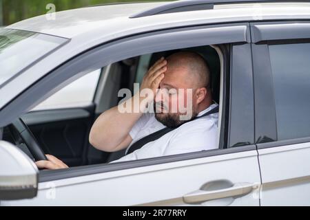 L'uomo in sovrappeso stanco guida l'auto con aria condizionata rotta in estate caldo tempo. Foto Stock