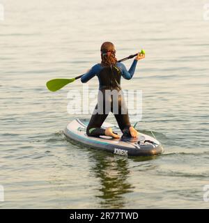 Un paddleboarder si avventurerà nel mare calmo, Boscombe, Dorset, Regno Unito, 13 giugno 2023, il tempo. Serate tranquille e molto calde dopo una giornata calda con venti molto leggeri. Foto Stock