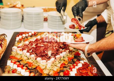 Cibo in stile italiano per matrimoni o feste, cameriere che serve gli ospiti Foto Stock