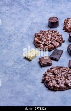 Varietà di prodotti di cioccolato fotografati in studio su sfondo grigio chiaro con texture bianca. Cioccolato fondente, cioccolato al latte, cioccolato bianco, c Foto Stock