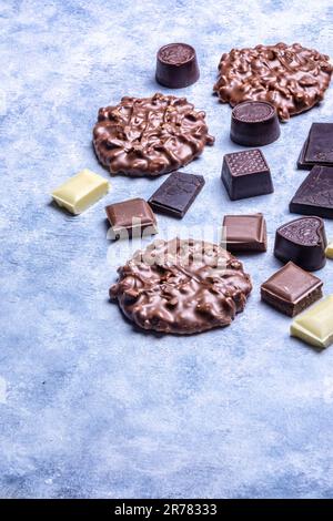 Varietà di prodotti di cioccolato fotografati in studio su sfondo grigio chiaro con texture bianca. Cioccolato fondente, cioccolato al latte, cioccolato bianco, c Foto Stock