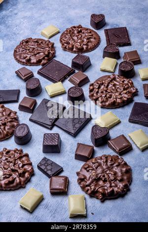 Varietà di prodotti di cioccolato fotografati in studio su sfondo grigio chiaro con texture bianca. Cioccolato fondente, cioccolato al latte, cioccolato bianco, c Foto Stock