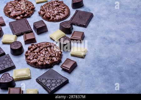 Varietà di prodotti di cioccolato fotografati in studio su sfondo grigio chiaro con texture bianca. Cioccolato fondente, cioccolato al latte, cioccolato bianco, c Foto Stock