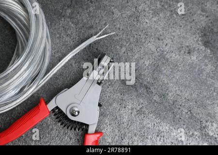 Taglierine e cavo con filo spelato su tavolo testurizzato grigio chiaro, piatto. Spazio per il testo Foto Stock