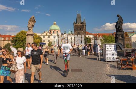 PRAGA, REPUBBLICA CECA - turisti che attraversano il Ponte Carlo, uomo in scooter. Torre del Ponte della Città Vecchia sul retro. Foto Stock