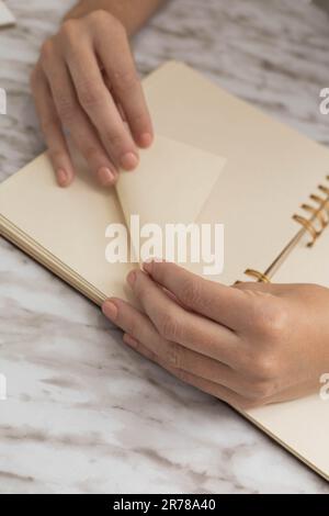 ripiegare il foglio di carta da un notebook, eseguire origami, attività creativa e artistica, dettagli di oggetti di cancelleria in studio Foto Stock