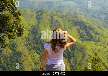 Giovane donna che gode di viste mozzafiato sulle montagne e le piantagioni di tè da Ella Peak in Ella Sri Lanka. Campi verdi, spazio di copia per il testo Foto Stock