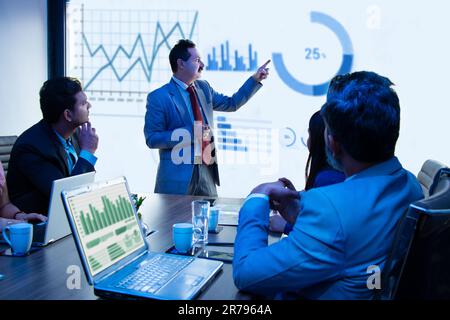 Presentazione delle riunioni degli uomini d'affari indiani nella sala conferenze dell'ufficio che mostra grafici infografici sullo schermo del proiettore, strategia di crescita del fatturato e ana Foto Stock