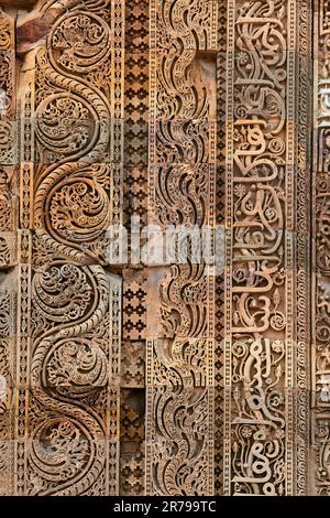 Motivi decorativi della parete del complesso Qutb a Delhi del sud, India, primo piano antiche decorazioni a bassorilievo della parete delle rovine della moschea punto di riferimento, popolare turista Foto Stock